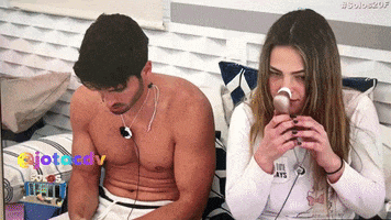 a shirtless man sits next to a shirtless woman who is wearing a white sweatshirt that says 100 cats