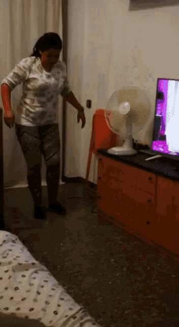 a woman dancing in front of a television in a room
