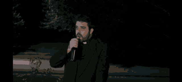 a person in a black cape is waving at the camera at night