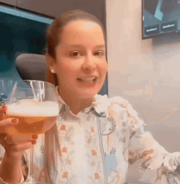 a woman is holding a glass of beer in her hand while sitting at a table .