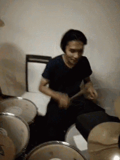 a man is playing drums in a dark room