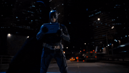 a man in a batman costume is holding a laptop