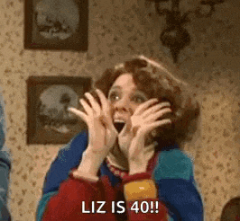 a woman is making a surprised face while holding her hands to her face and saying `` liz is 40 '' .