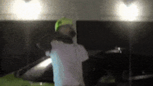 a man wearing a neon green hat is standing in front of a green car .
