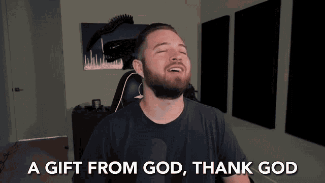 a man with a beard is sitting in front of a microphone and says a gift from god thank god .
