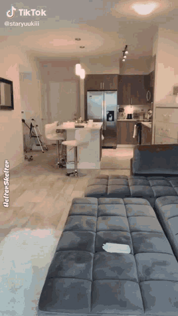 a tiktok video of a living room with a couch and kitchen
