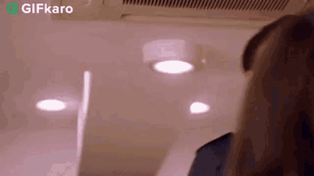 a woman is standing in front of a ceiling fan .