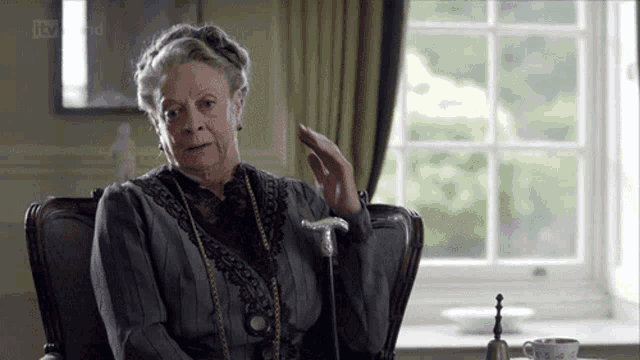 a woman sitting in a chair with a cane and a tv screen behind her that says itv
