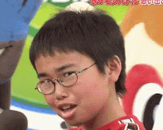 a young boy wearing glasses and a red shirt is making a face .