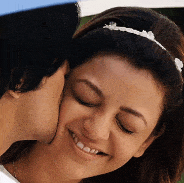 a man kisses a woman on the cheek and she smiles
