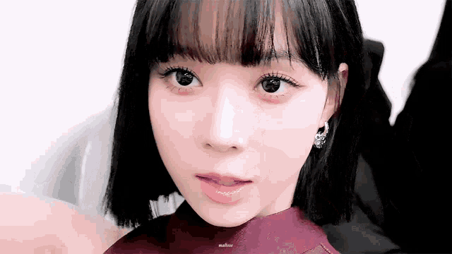 a close up of a girl 's face with short hair and bangs .