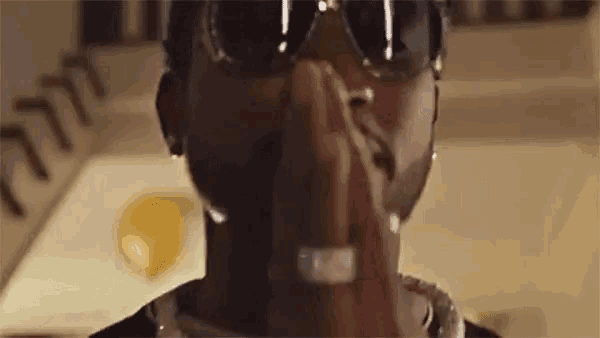 a close up of a man wearing sunglasses and a ring covering his face .