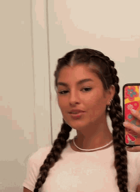 a woman is taking a selfie in front of a mirror with her hair in braids .