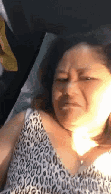 a woman in a leopard print top is laying on a bed and making a funny face