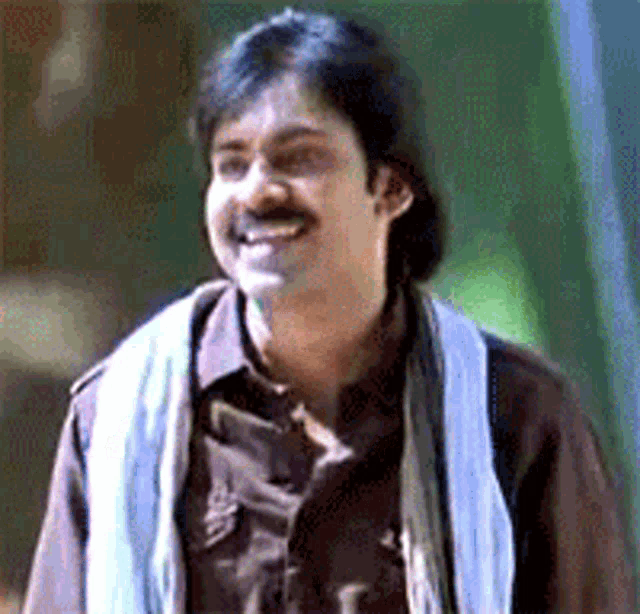 a man wearing a brown shirt and a white scarf is smiling .