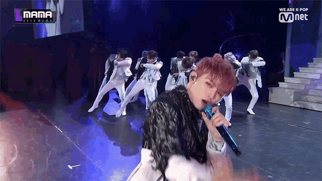 a man singing into a microphone on a stage with a sign that says we are k pop