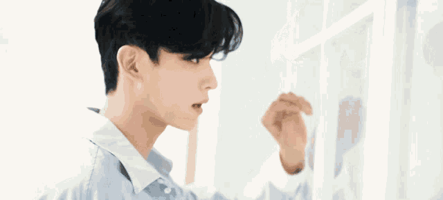 a young man in a white shirt is looking at a picture frame