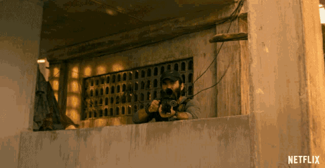 a man holding a gun in front of a building that says netflix on the bottom