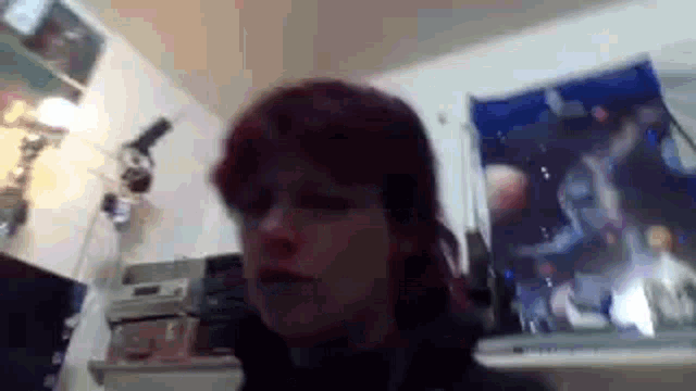 a woman with red hair is looking at the camera in a room with a picture of the moon on the wall .