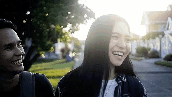 a man and a woman are walking down a sidewalk and smiling
