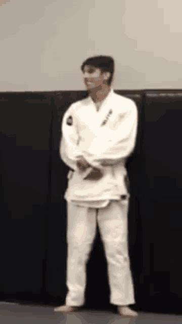 a man in a white karate uniform is standing in front of a wall .