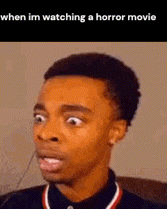 a man with a surprised look on his face is watching a horror movie .