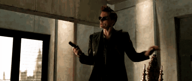 a man in a suit and sunglasses holds a gun in his hand