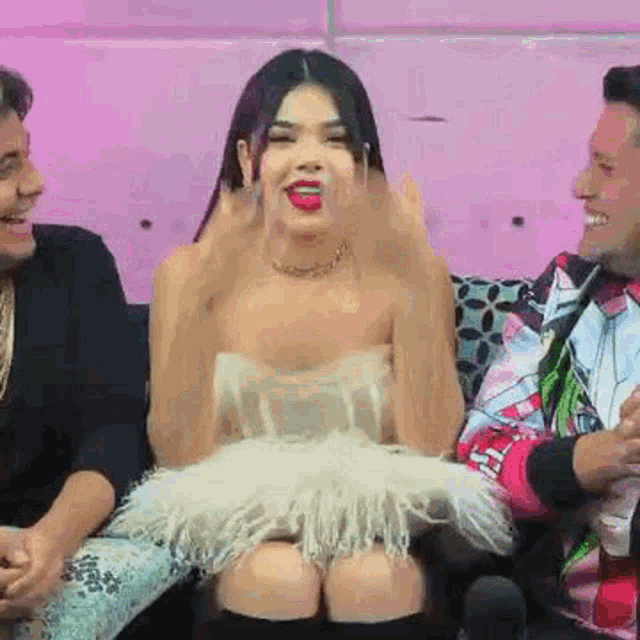 a woman in a white dress is sitting on a couch with two men .