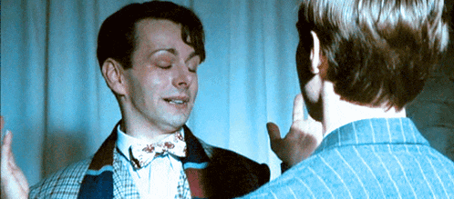 a man in a bow tie is talking to another man in a suit