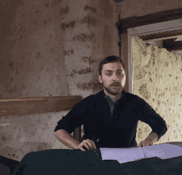 a man with a beard is sitting at a table with papers