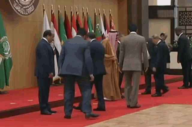 a group of men in suits standing on a red carpet