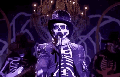 a skeleton is singing into a microphone in a band .