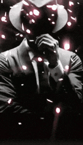 a man in a suit and hat holds his hand to his face