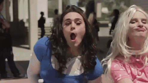 a man in a blue shirt is yawning next to a blonde woman in a pink shirt .