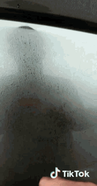 a close up of a person 's hand on a window with a tiktok logo on the bottom