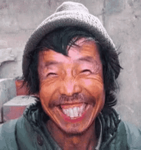a man wearing a hat and a green jacket is smiling .