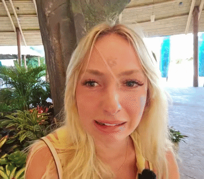 a close up of a blonde woman 's face with a tree in the background