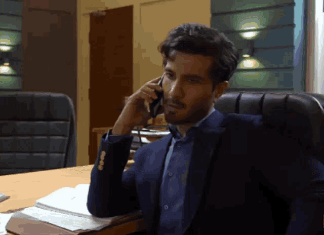 a man in a suit talks on a cell phone