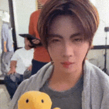 a young man is holding a stuffed duck and making a face .