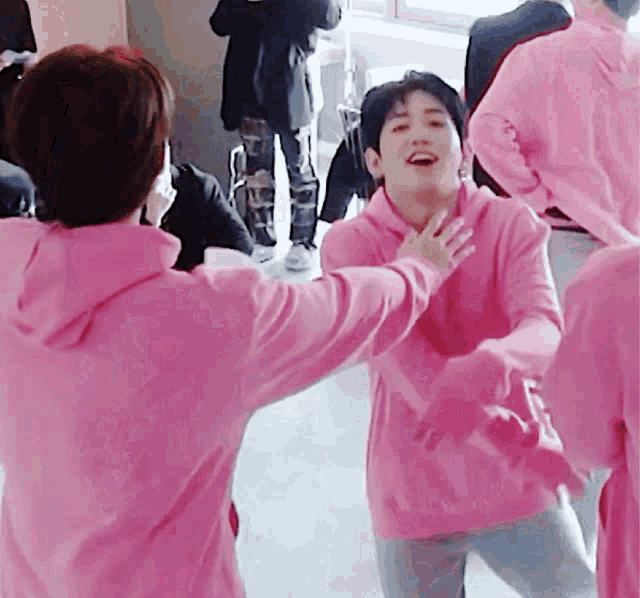 a group of people in pink hoodies are hugging each other