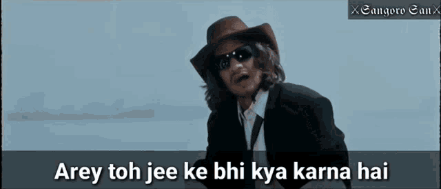 a man in a suit and cowboy hat says arey toh jee ke bhi kya karna hai