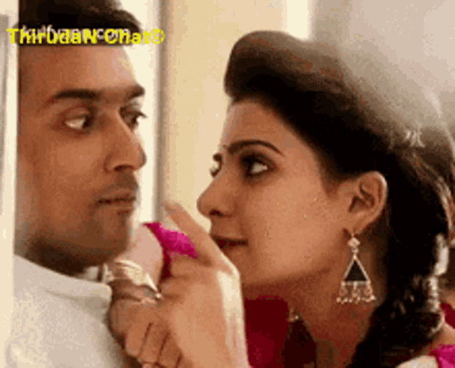 a woman is touching a man 's face with her finger .