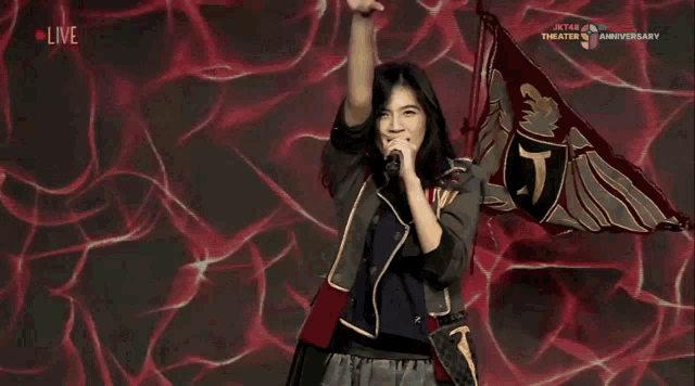 a woman singing into a microphone while holding a flag that says jt on it
