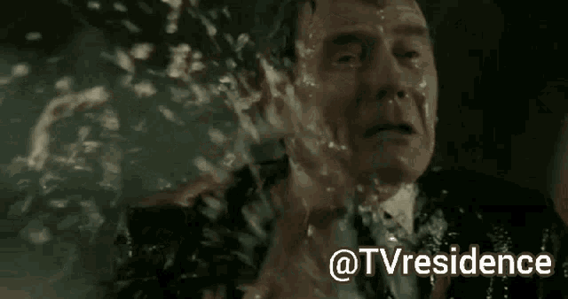 a man in a suit and tie is crying with water coming out of his face .