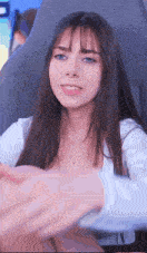 a woman with long hair and blue eyes is sitting in a chair and smiling at the camera .