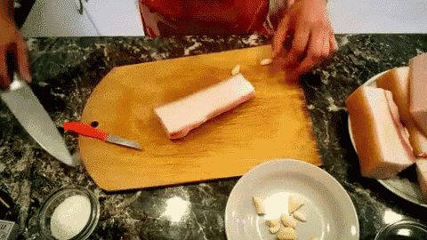 a person is cutting a piece of meat on a cutting board with a knife