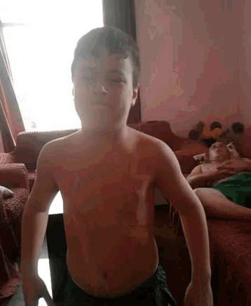 a boy without a shirt is standing in a living room