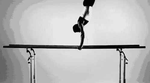 a black and white photo of a gymnast on a balance beam .