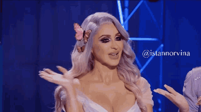 a woman in a white dress says hi guys in front of a blue background