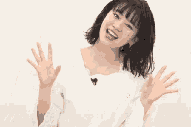 a young woman in a white shirt is making a funny face with her hands outstretched .